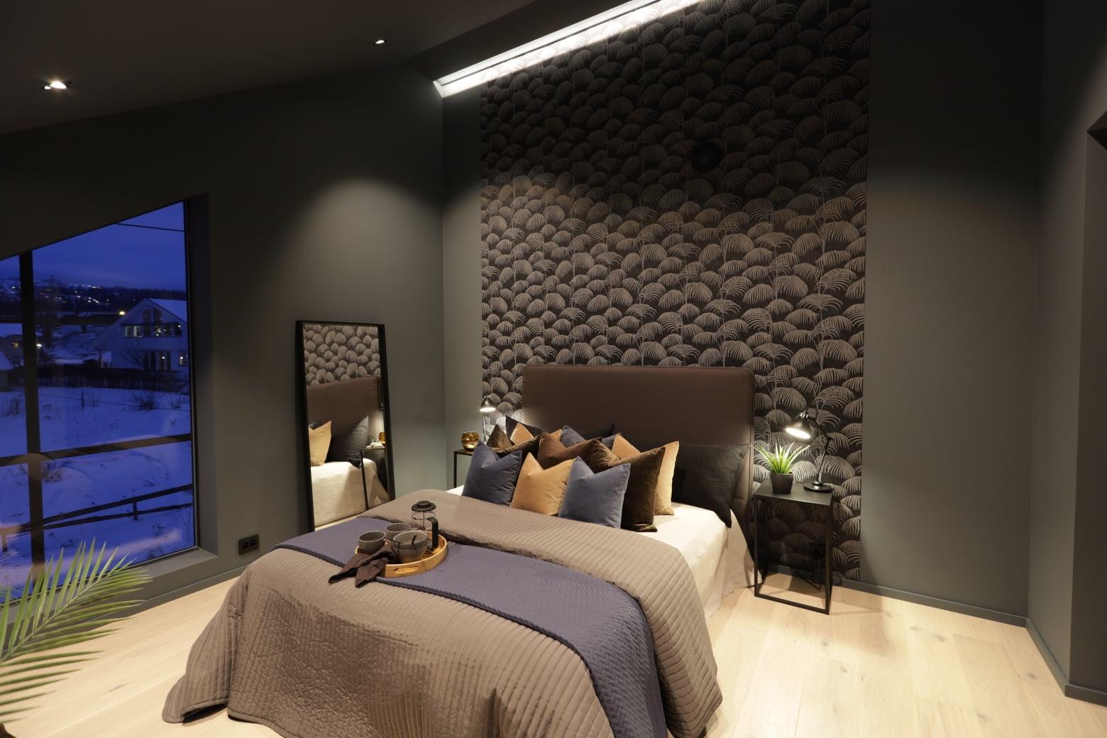 A bedroom with a dark stone feature wall behind the bed