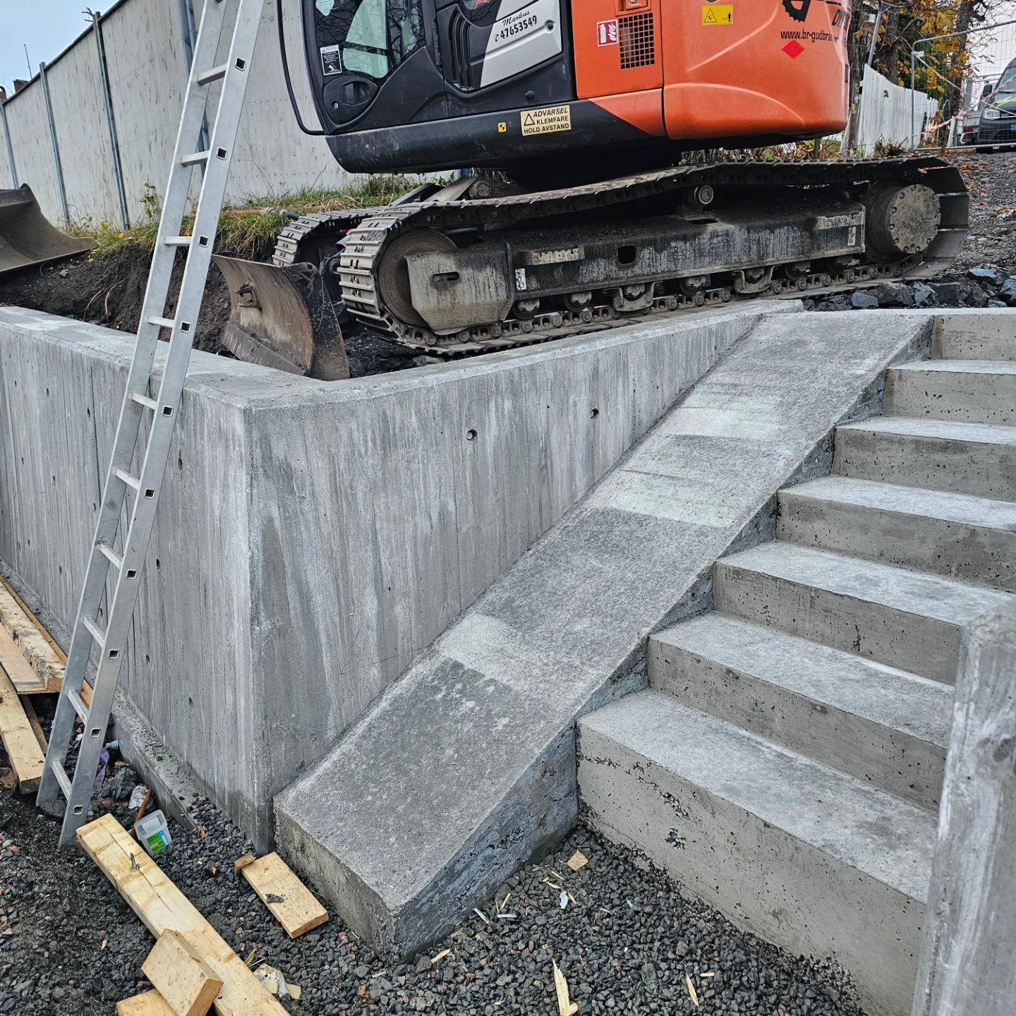 New concrete steps and a retaining wall, with a digger behind
