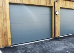 Two new grey garage doors in a timber-clad garage