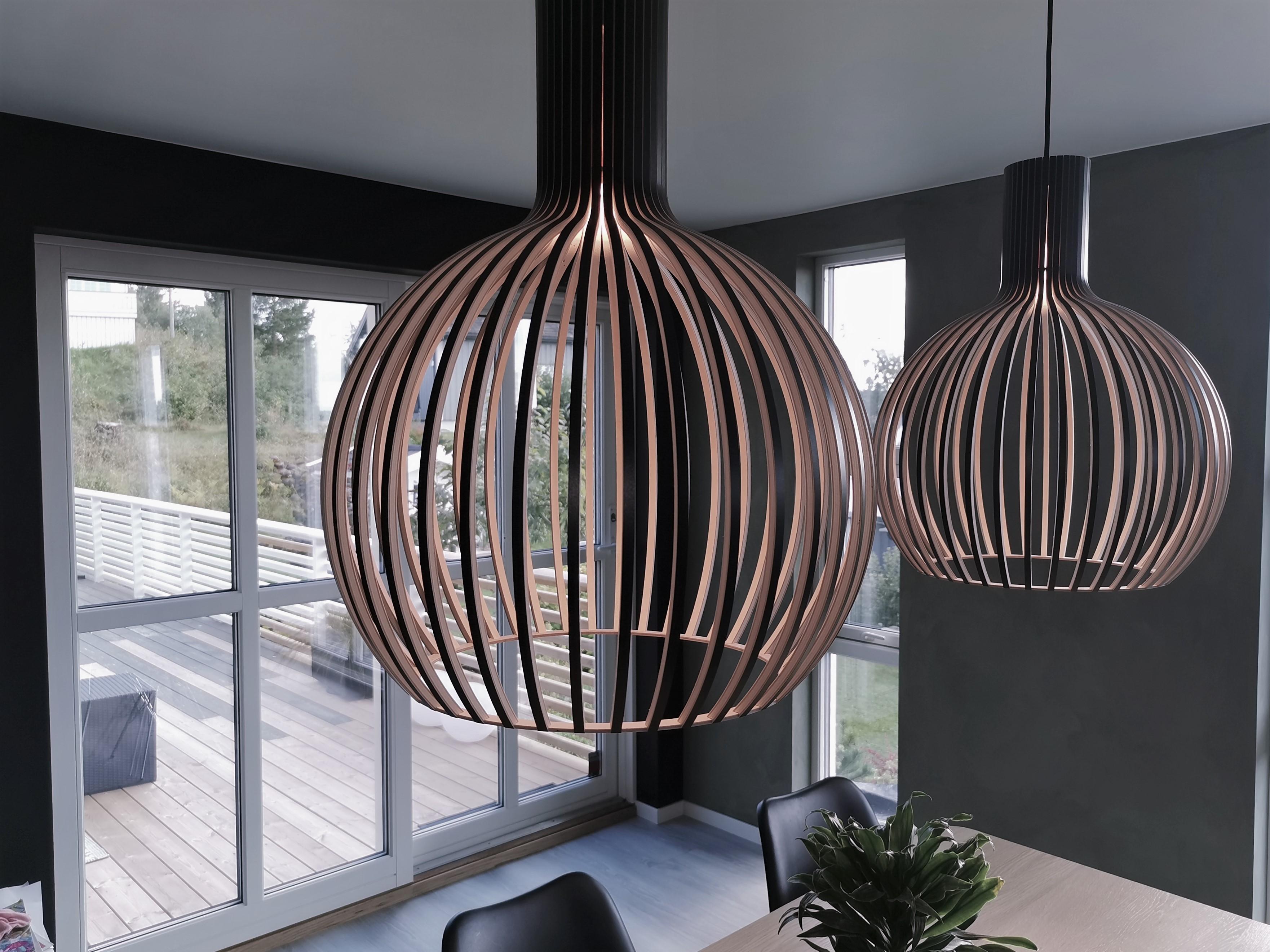 Two large wooden pendant lamps in front of glass doors to a terrace