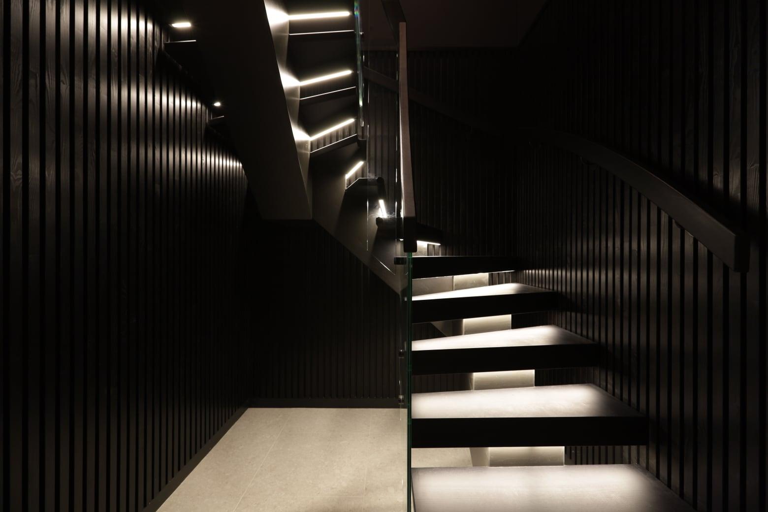 A dark staircase with lights set into the wall beside each step